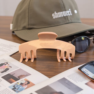 Cashmere blush nude hat claw clip displayed beside a trucker hat and sunglasses, designed for comfortable hairstyles while wearing hats.