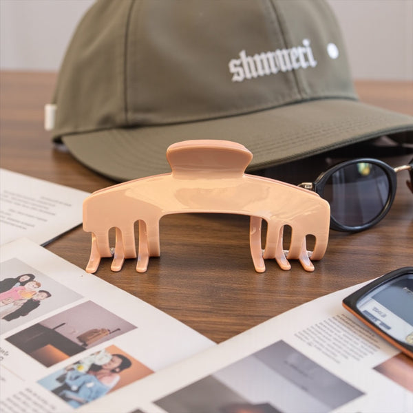 Cashmere blush nude hat claw clip displayed beside a trucker hat and sunglasses, designed for comfortable hairstyles while wearing hats.