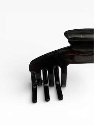 Close-up of the Eclipse glossy black hat claw clip highlighting the smooth finish, curved teeth, and low-profile shape.