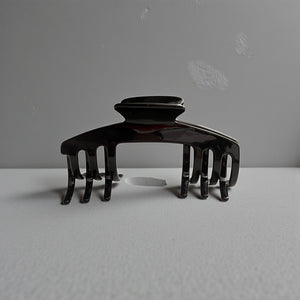 Eclipse glossy black hat claw clip displayed on a neutral surface, highlighting its sleek finish and everyday style.