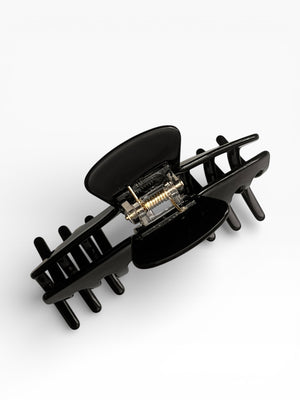 Top view of the Eclipse glossy black hat claw clip showing the spring hinge, teeth, and secure grip design.