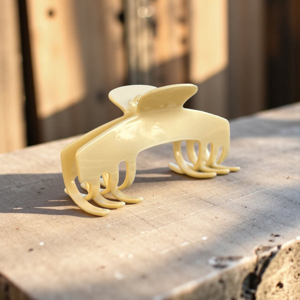 Ivory cream hat claw clip displayed outdoors in warm light, showing its neutral finish and secure everyday design.