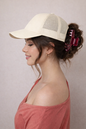 Woman wearing a beige cap and pink top against a plain background using Merlot hat clip by Baddie Clip