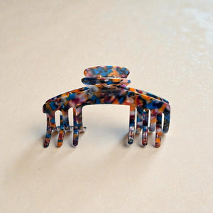 Mosaic multicolor tortoiseshell claw clip displayed upright in a neutral lifestyle setting.
