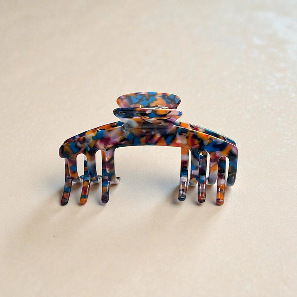 Mosaic multicolor tortoiseshell claw clip displayed upright in a neutral lifestyle setting.