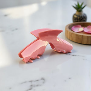 Muse pink hat claw clip displayed on a countertop, showcasing its soft pink finish and everyday style.