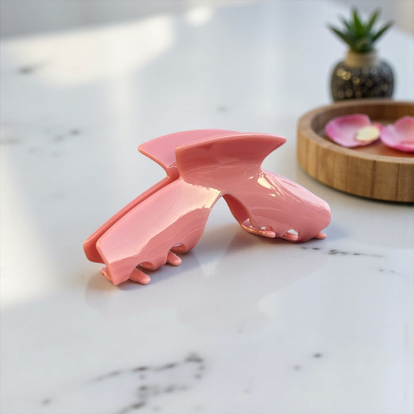 Muse pink hat claw clip displayed on a countertop, showcasing its soft pink finish and everyday style.