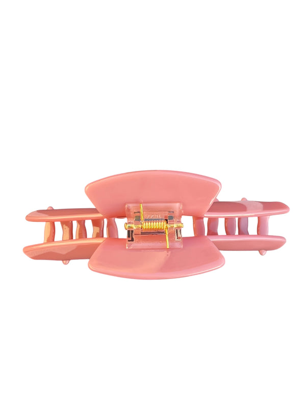 Top view of the Muse pink hat claw clip showing the spring hinge and curved teeth.