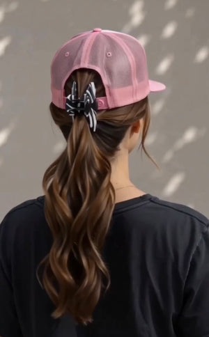 Noir black and white hat claw clip securing a ponytail hairstyle while wearing a pink baseball cap.
