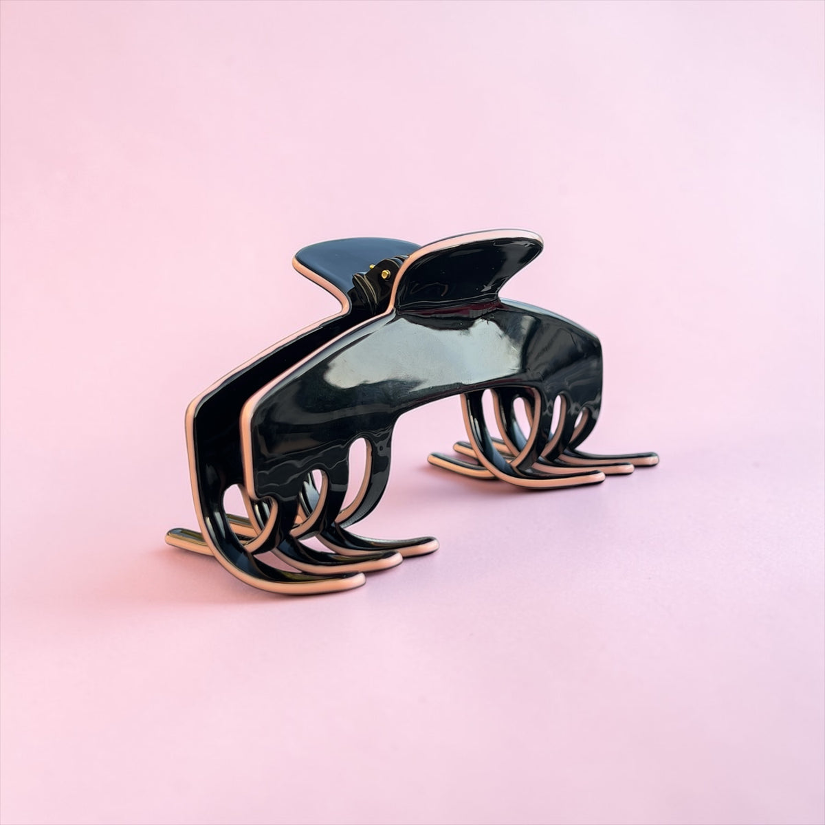 Onyx Black hair clip for hats with baby pink accents on a pink background