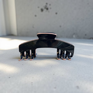 Onyx black hat claw clip displayed on a clean surface, highlighting its sleek finish and everyday Power Hold design.