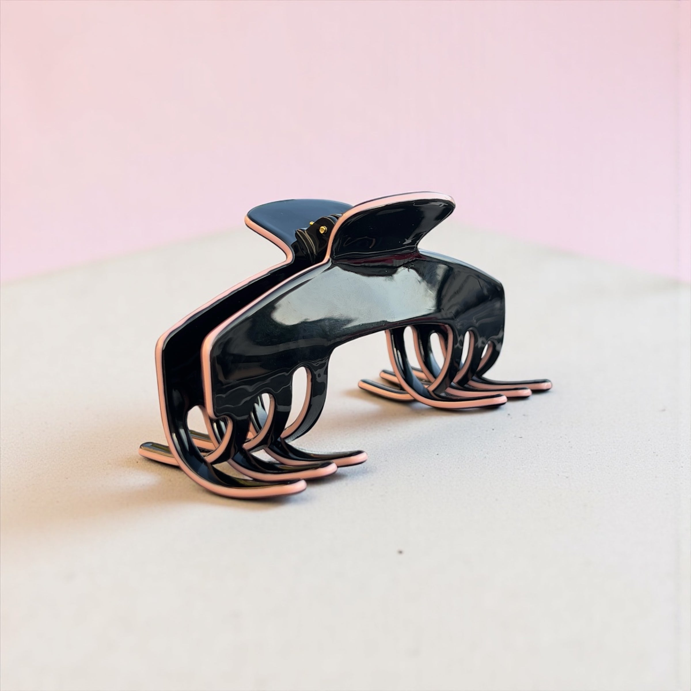 Black and light pink Onyx hair claw for hat from Baddie Clip on a light pink background