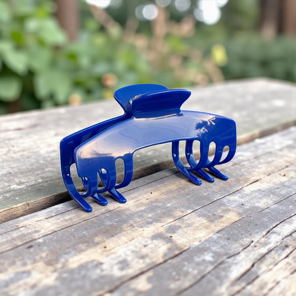 Relentless cobalt blue hair claw clip displayed outdoors on a wooden table. Durable claw clip for hats designed to securely hold thick, long, and textured hair.