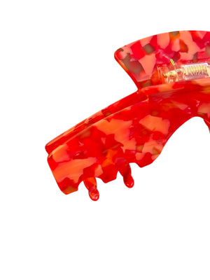 Close-up of the Scarlet red mosaic hat claw clip showing the spring hinge, glossy finish, and curved grip teeth.