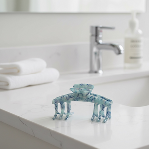 Sea Glass blue marble claw clip displayed on a bathroom counter in a bright neutral setting.