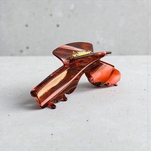 Siren amber tortoise hat claw clip displayed outdoors, highlighting its stylish finish and secure hold for everyday wear.