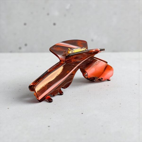 Siren amber tortoise hat claw clip displayed outdoors, highlighting its stylish finish and secure hold for everyday wear.