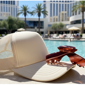 Siren amber tortoise hat claw clip beside a baseball hat at the pool, offering a stylish and secure hold for medium, thick, and long hair.