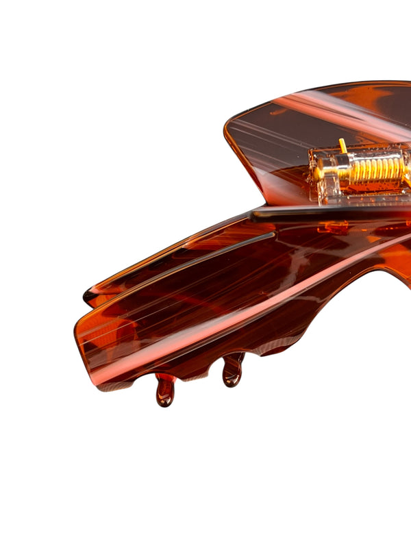 Side detail of the Siren amber tortoise claw clip showing the strong spring and curved teeth for a comfortable, secure grip.