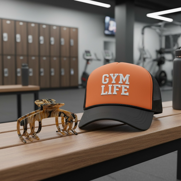 Tortoise brown marble hat claw clip displayed beside an orange trucker hat in a gym setting, designed for comfortable hat hairstyles.